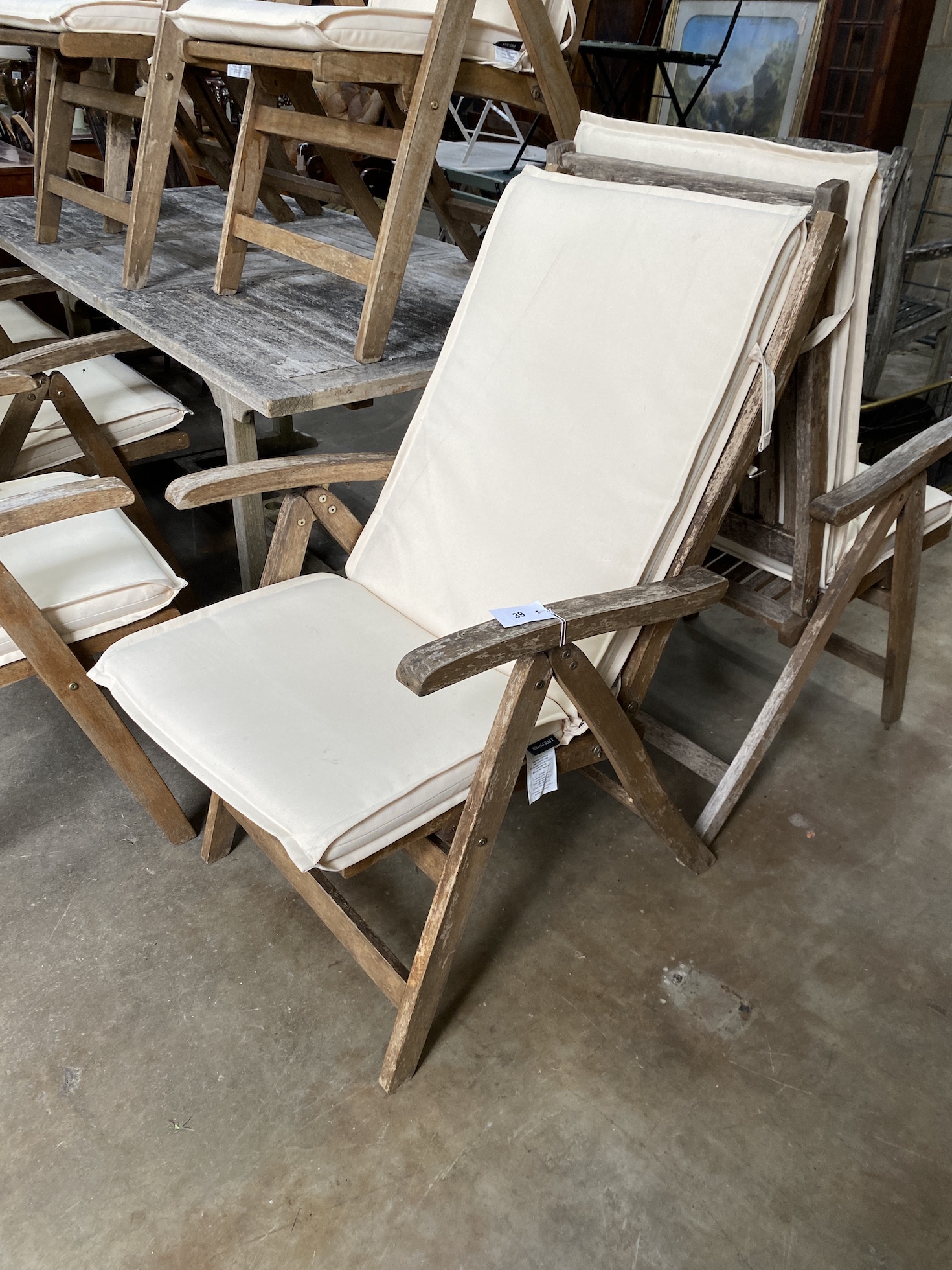 A Lindsey rectangular weathered teak extending garden table, 200cm extended, depth 94cm, height 75cm and eight Royal teak folding garden elbow chairs with seat cushions